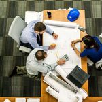 Top view of a team working on construction plans in an office setting.